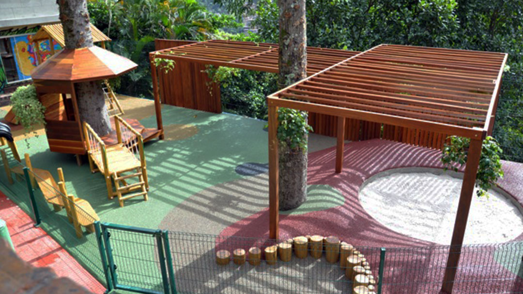 playground com piso ecológico de borracha colorido da pisoleve em área externa, com pergolado de madeira e brinquedos infanti