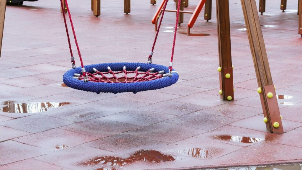 playground com piso de borracha apresentando acúmulo de água em poças, exemplo de erro por falta de drenagem adequada